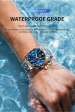 Trendy men's watch with blue dial and gold case, worn on wrist against water background